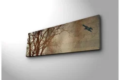 Lerretsbilde med LED-belysning 30x90 cm - Silhuett av et tre med en fugl i flukt mot en mykt tonet bakgrunn